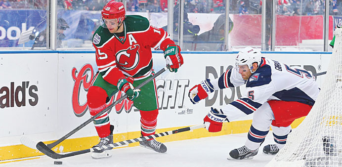 New Jersey Devils center Travis Zajac (left) carries the puck past New York Rangers defenseman Dan Girardi during the third period of the Stadium Seri