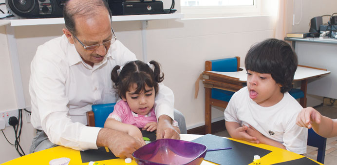 Children being assisted by teachers during art workshops.