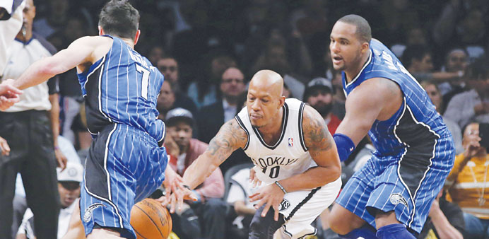 Brooklyn Nets forward Keith Bogans cuts between Orlando Magic guard J J Redick and forward Glen Davis to steal the ball in the fourth quarter of their