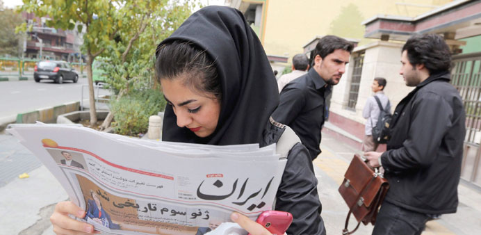    A girl reading a copy of the Iran newspaper with a headline translating u201cThird Geneva was historicalu201d outside a kiosk in a Tehran yesterday.