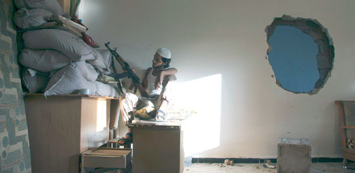 A Free Syrian Army fighter takes cover behind sandbags inside a house in Deir al-Zor on Tuesday.
