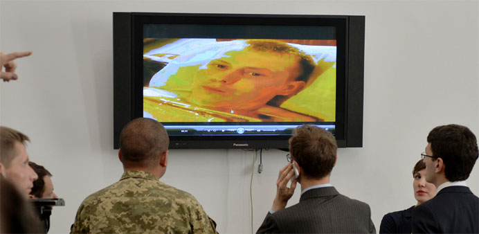 Journalists and an officer watch a video allegedly  showing a Russian soldier, captured during recent battles 