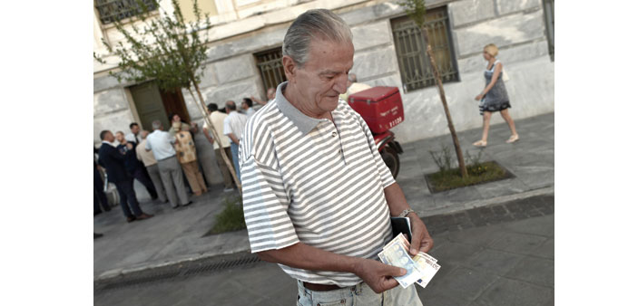  A pensioner holds banknotes next to people waiting outside a bank.