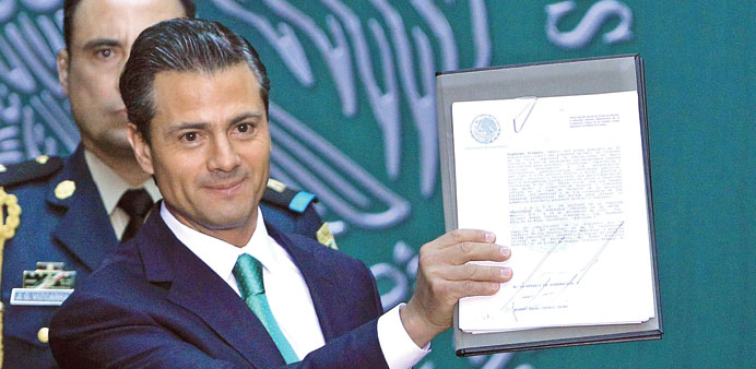 Pena Nieto shows the document that promulgates the constitutional energy reform, during an event in Mexico City on Friday.