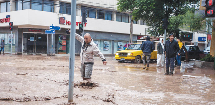 A man wades across a street flooded by the river Copiapo overflowing after heavy rainfall that affected some areas in the city of Copiapo, Chile.