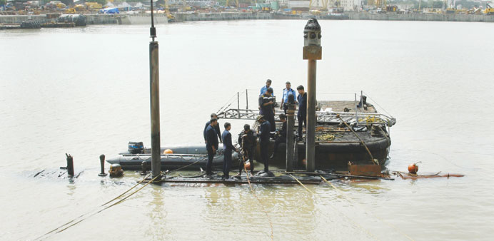 Navy divers standing on the INS Sindhurakshak submarine prepare to dive into the waters of the Arabian Sea during a rescue operation in Mumbai.