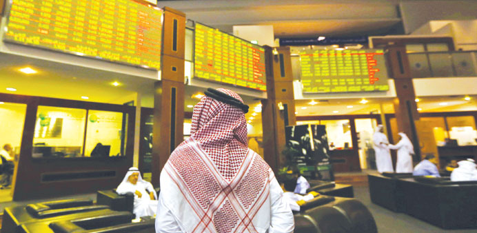 An investor looks up at screens displaying stock information at the Dubai Financial Market. Dubaiu2019s bourse was hit hard yesterday, plunging 3.7% to to