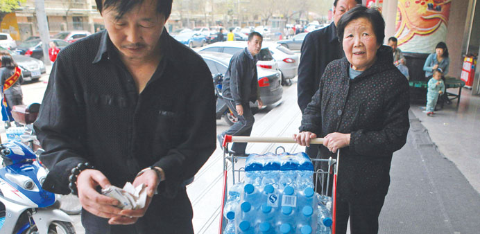 A woman pushes a cart full of bottled water outside a supermarket in Lanzhou after the government warned citizens not to drink tap water.