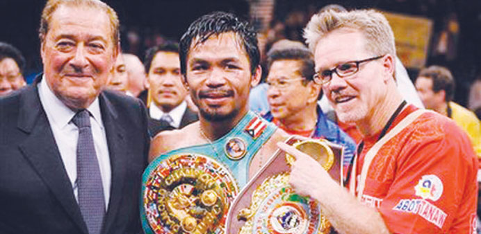 Manny Pacquiao (centre) holds his championship belt as he stands with promoter Bob Arum (left) and trainer Freddie Roach after winning his WBO welterw