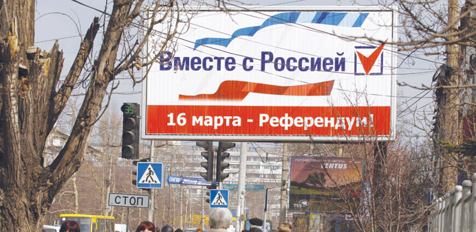 People walking under a sign that reads, u201cTogether with Russia. March 16 - referendumu201d, in the centre of Simferopol, Crimea, yesterday.