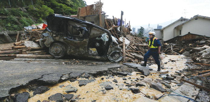 A rescue worker walks at the site of a landslide to search for missing people in a residential area in Hiroshima.