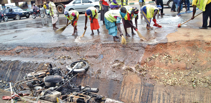 Nigerian workers clean the site of a bomb blast in Abuja yesterday.