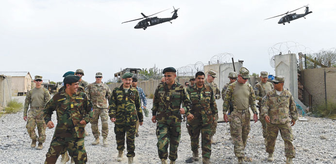 US army and Afghan National Army (ANA) soldiers walk as Nato helicopters fly overhead at coalition force Forward Operating Base (FOB) Connelly in the 
