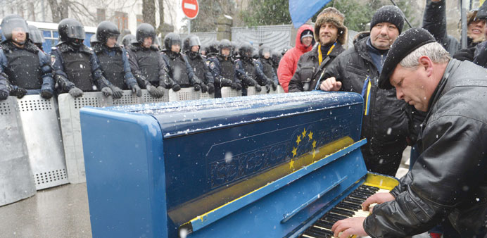 A man plays on a piano decorated with EU flag yesterday in front of riot police as protesters picket Viktor Yanukovychu2019s presidential office in Kiev.