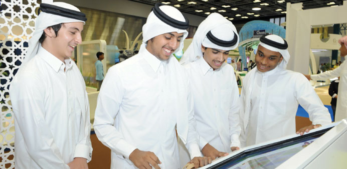 Students learn from a interactive touchscreen at the Qatargas booth
