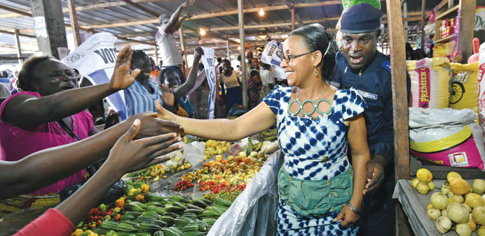 Independent presidential candidate Jacqueline Claire Kouangoua shakes hands with people during a visit to a market as part of her campaign in Abidjan 