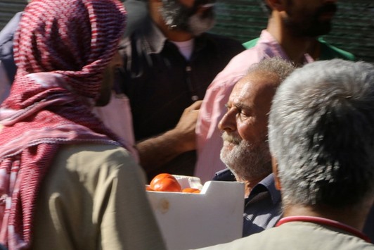 A man carries a box of tomatoes he received as food aid in Aleppo yesterday.