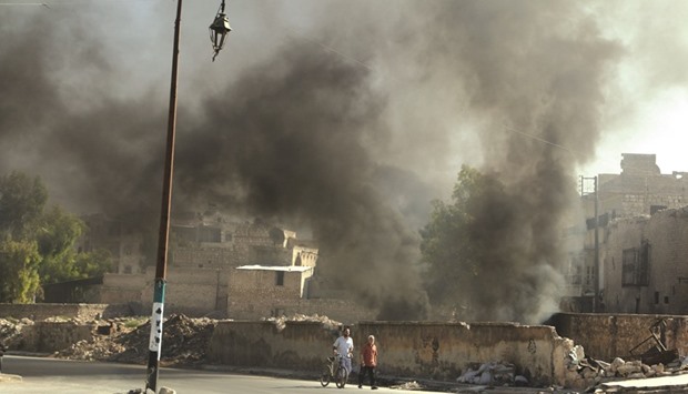Men walk past burning tyres, which activists said are used to create smoke cover from warplanes, in Aleppo yesterday.