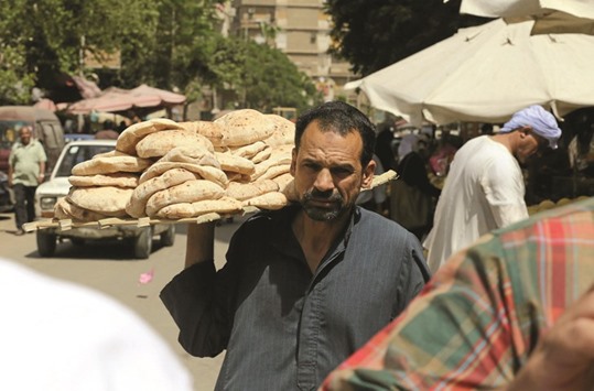 An Egyptian man holds bread in the vegetables market in Cairo. Egypt has struggled to spur economic growth and attract foreign investments since the 2011 uprising that ousted former president Hosni Mubarak.