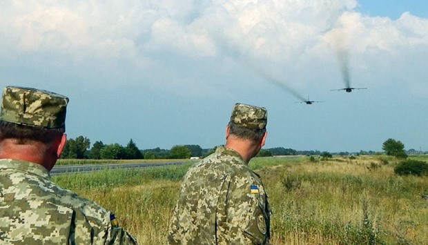 Ukrainian servicemen watch Sukhoi Su-24 front-line bombers fly during military aviation drills in Rivne region, Ukraine, as Russia accuses Ukraine of incursions into annexed Crimea.