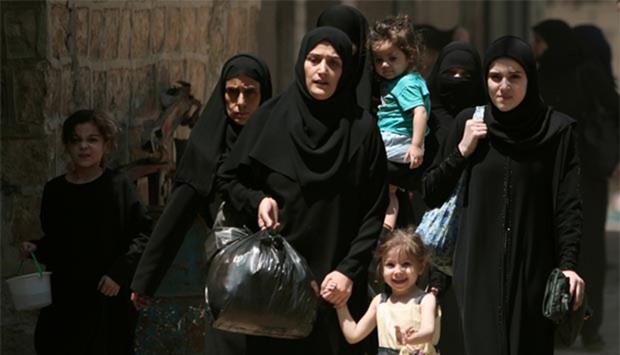 Syrian women and children carry belongings and they flee towards safer parts of Manbij city, in Aleppo governorate, this week.