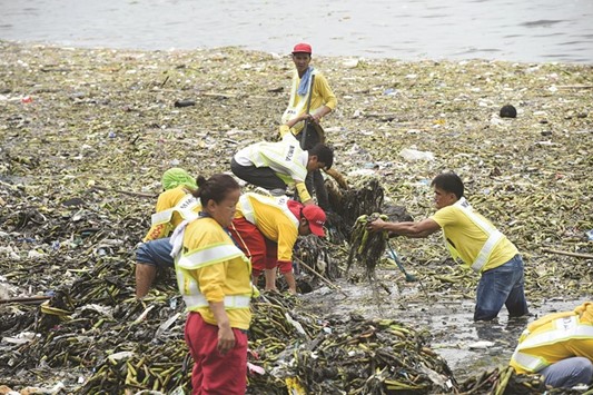 Workers collect floating garbage at Manila baywalk, washed ashore after tropical storm Carina passed through northern Philippines yesterday.