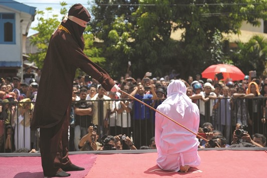 A religious officer canes a woman onstage outside a mosque in Banda Aceh yesterday.