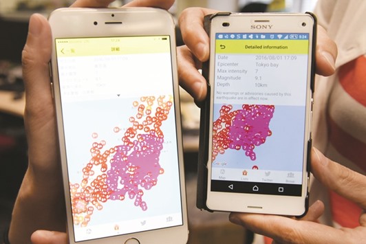 This photo illustration shows people with their smartphones showing yesterday an erroneous mega-earthquake alert with a magnitude of 9.1 on the Richter scale, and an intensity of 7 out of 7 on the Japanese scale, for Tokyo Bay. A false warning of a megaquake about to strike Tokyo was issued by Japanu2019s weather agency and quickly cancelled, but not before terrifying users of a smartphone app who received it.