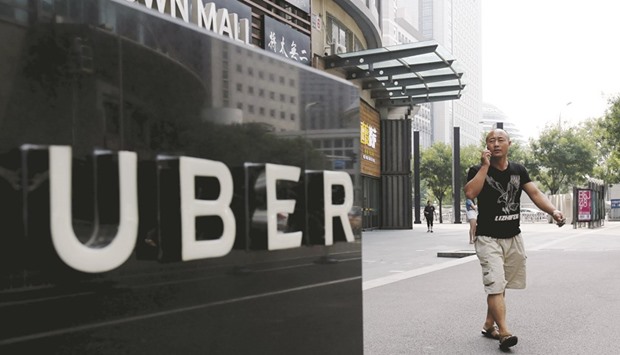 A man walks past an Uber station outside a shopping mall in Beijing. The ride-sharing giant is to merge its China operations with local rival Didi Chuxing, reports said yesterday, ending a ferocious battle for market share in the worldu2019s second-largest economy.