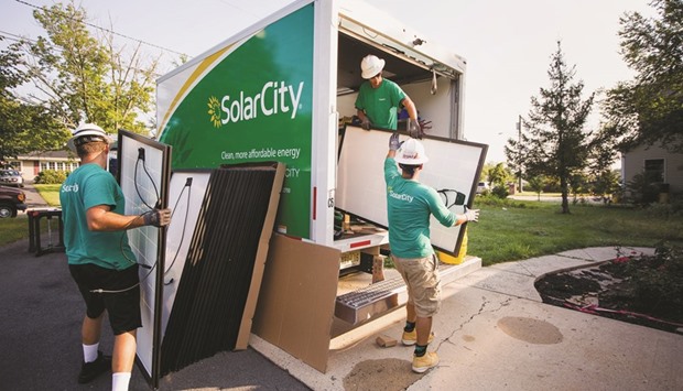 SolarCity Corp employees unload solar panels from a truck during a home installation in Kendall Park, New Jersey. SolarCity became the biggest US rooftop solar company largely by focusing on growth at the expense of profit, and investing revenue into building more systems.