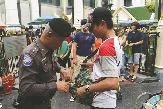 A Thai policeman searches a visitoru2019s bag at the Erawan Shrine, the site of a bombing in August 2015 that left 20 dead and scores injured, in the centre of Bangkok yesterday as authorities increase security following a new string of bomb attacks in Thailand.