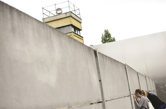 People look through a crack at the Berlin Wall Memorial at Bernauer Strasse in Berlin.