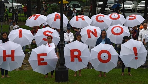 Protesters hold umbrellas with an anti-Marcos slogan during a demonstration at a park in Manila on Sunday against plans to honour the late dictator Ferdinand Marcos with a state burial.