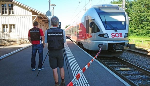 Policemen stand by a train at the station in Salez, eastern Switzerland, after a man set fire and stabbed passengers on Saturday.