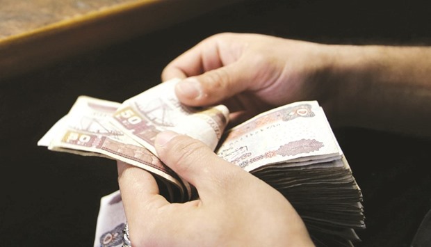 A customer counts his Egyptian 50 pound notes at an exchange office in downtown Cairo. The IMF deal paves the way for a series of measures that economists say will likely include a new round of devaluation or flexible exchange rate to attract foreign investments to the nationu2019s economy, bond and stock markets.
