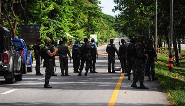 Thai soldiers watch as a forensic unit inspects the scene of an attack following two roadside bomb blasts in the Bacho district of the southern province of Narathiwat on Monday.