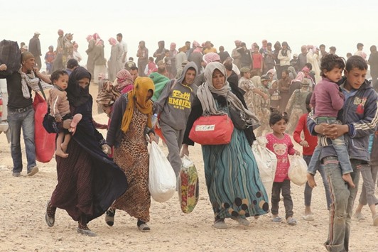 Syrian refugees carrying their belongings as they wait to enter Jordanian side of the Hadalat border crossing, a military zone east of Amman, after arriving from Syria.