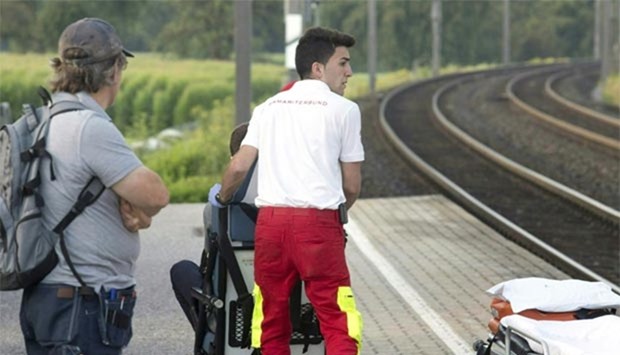 A man looks on as a paramedic pushes a wheelchair over a platform on Tuesday at the train station Sulz-Ru0650this in Vorarlberg, Austria, after a suspect attacked two train passengers with a knife.