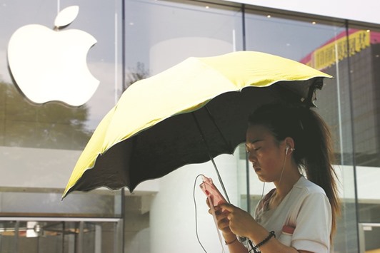 A woman uses a phone outside an Apple store in Beijing. Demand for Appleu2019s phones has plummeted in China, and the government maintains a wary attitude towards foreign technology, chief executive Tim Cook said yesterday.