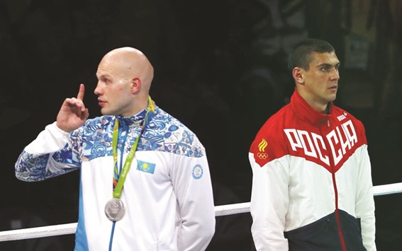 Silver medallist Vassiliy Levit (KAZ) of Kazakhstan reacts to the audience as gold medallist Evgeny Tishchenko (RUS) of Russia stands at attention for the singing of the national anthem.