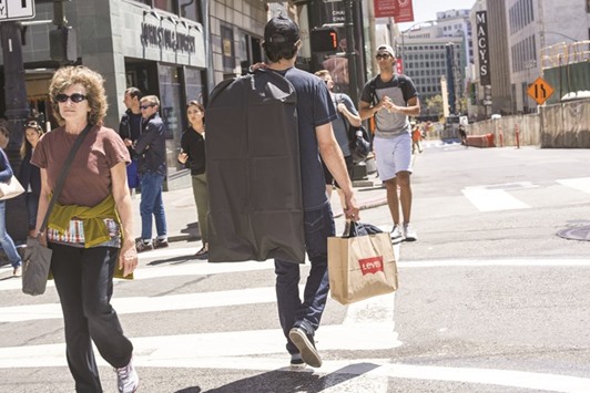 A shopper carries a Levi Strauss & Co bag while crossing Post Street in San Francisco. Julyu2019s flat reading in the Consumer Price Index in the US was the weakest since February and followed two straight monthly increases of 0.2%.
