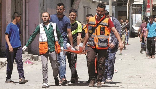 Members of the Palestinian Red Crescent and medics evacuate on a stretcher a Palestinian youth who was wounded during clashes with Israeli soldiers conducting searches in the Palestinian al-Fawwar refugee camp, south of the West Bank city of Hebron, yesterday.