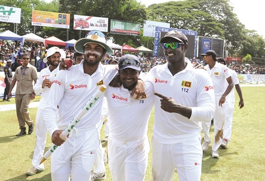 Sri Lankau2019s captain Angelo Mathews (R) celebrates with teammates Rangana Herath (C) and Dinesh Chandimal after victory in the third and final Test match between Sri Lanka and Australia.