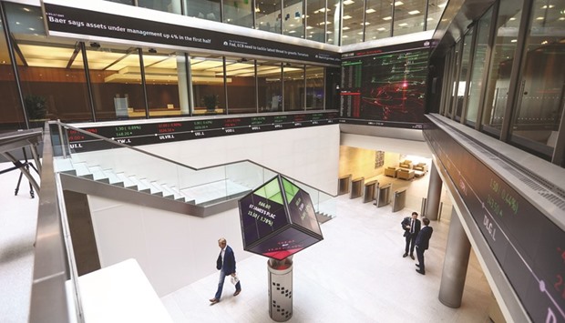 A visitor walks past an illuminated rotating cube in the atrium of the London Stock Exchange Groupu2019s offices in Paternoster Square. Londonu2019s benchmark FTSE 100 index closed down 0.15% at 6,858.95 points yesterday.