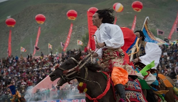 Ethnic Tibetans ride horses in traditional dress