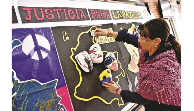 Colombian art teacher Zully Aldana places plaster masks made by students of class on a billboard at the Heladia Mejia school in Bogota in the framework of a national education initiative for peace.