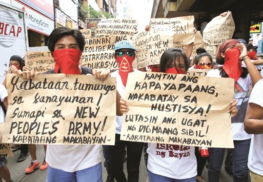 Supporters of the communist group National Democratic Front (NDF) of the Philippines cover their faces while displaying placards during a protest march calling for the resumption of peace talks between the government and the Maoist-led rebels, along a main thoroughfare in metro Manila, yesterday. Placard reads at L-R: u201cYouth head to the rural provinces! Join the New Peopleu2019s Army!u201d u201cAttain peace based on justice! Resolve the roots of civil war.u201d