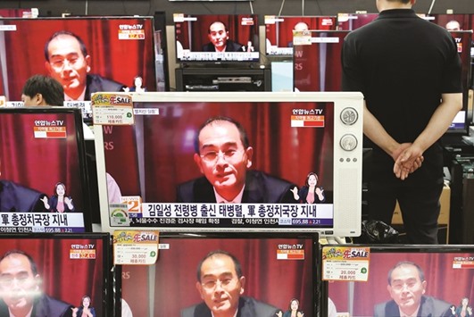 This picture taken on Thursday shows a sales assistant in Seoul watching TV sets broadcasting a news report on Thae.