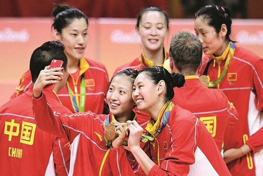 Gold medallist Chinau2019s Ding Xia (L) poses for a selfie on the podium after the womenu2019s Gold Medal volleyball match.