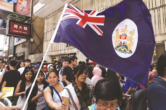 The British colonial-era Hong Kong flag is seen as pedestrians walk past a holding area for demonstrating activists ahead of a rally against the banning of pro-independence candidates in the upcoming legislative council elections.